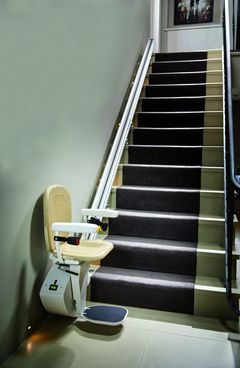 Gerader Treppenlift in Parkposition vor einer Treppe mit Teppichbelag