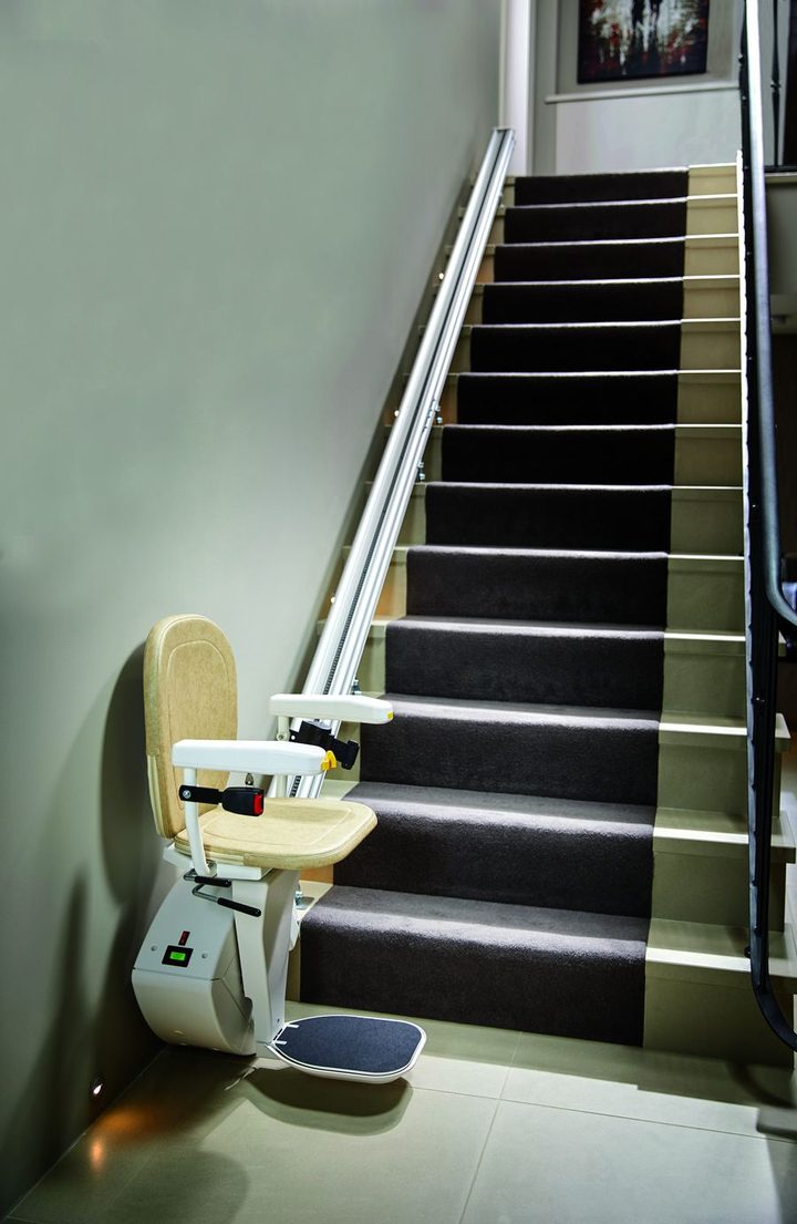 Gerader Treppenlift in Parkposition vor einer Treppe mit Teppichbelag